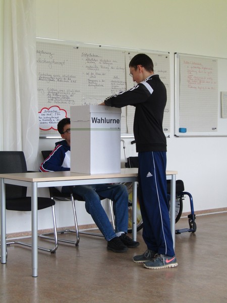 Schüler wirft Stimmzettel in die Wahlurne.